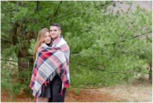 winter engagement session in evergreen trees plaid blanket