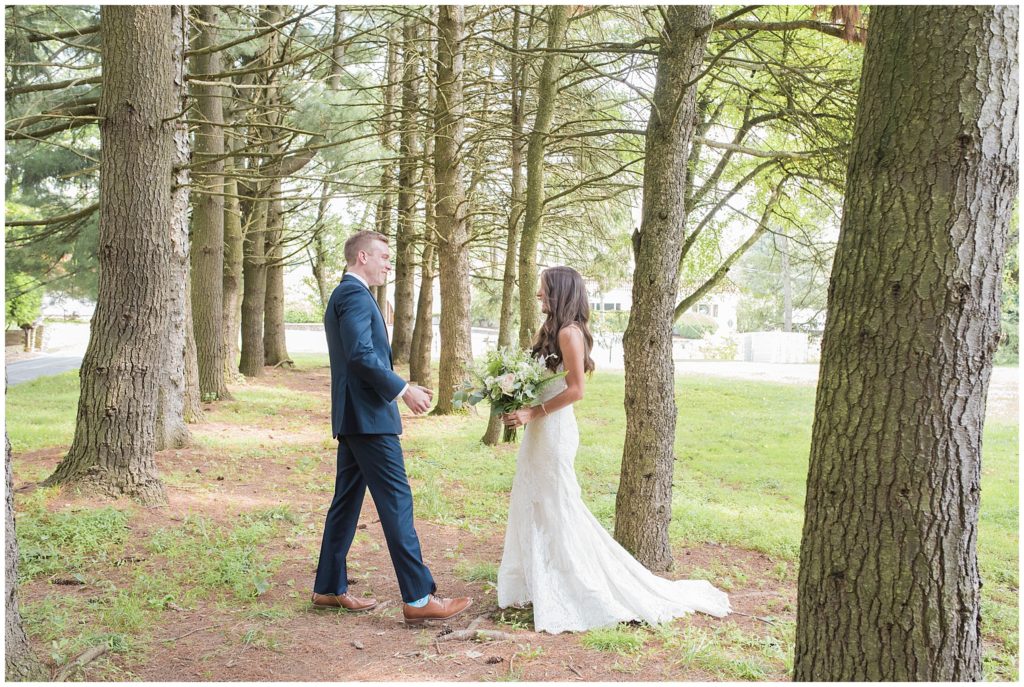 bride and groom first look in path under trees