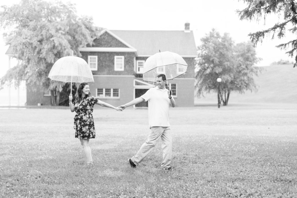 couple holding hands walking with umbrellas in rain