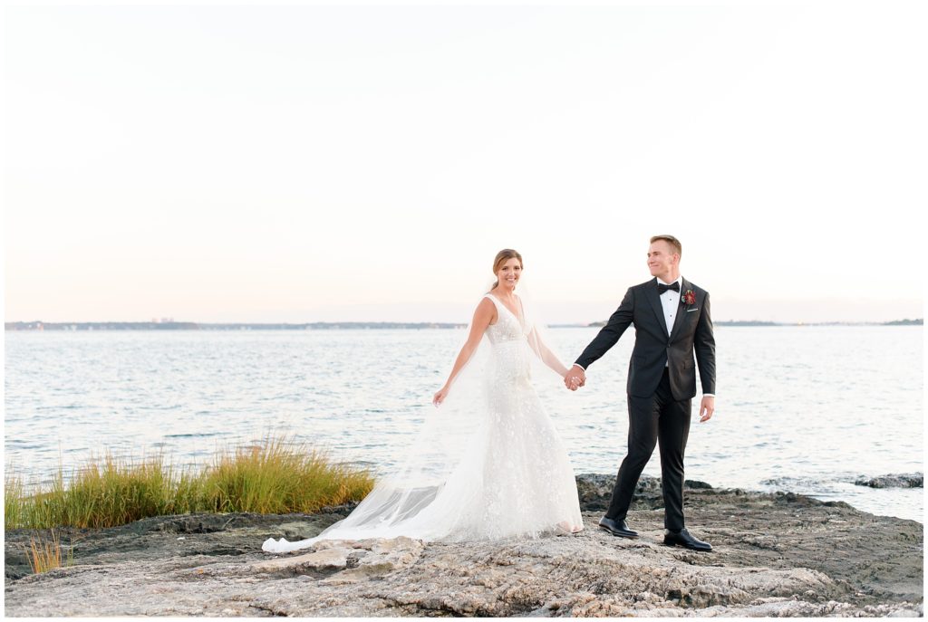 bride and groom on rock on waterfront