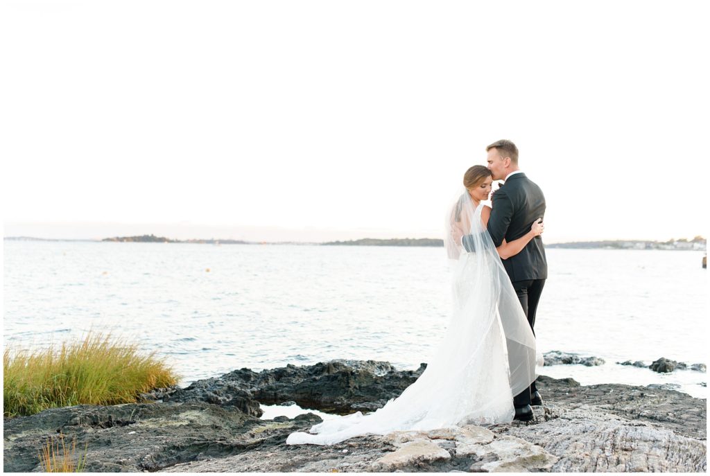 bride and groom on rock on waterfront